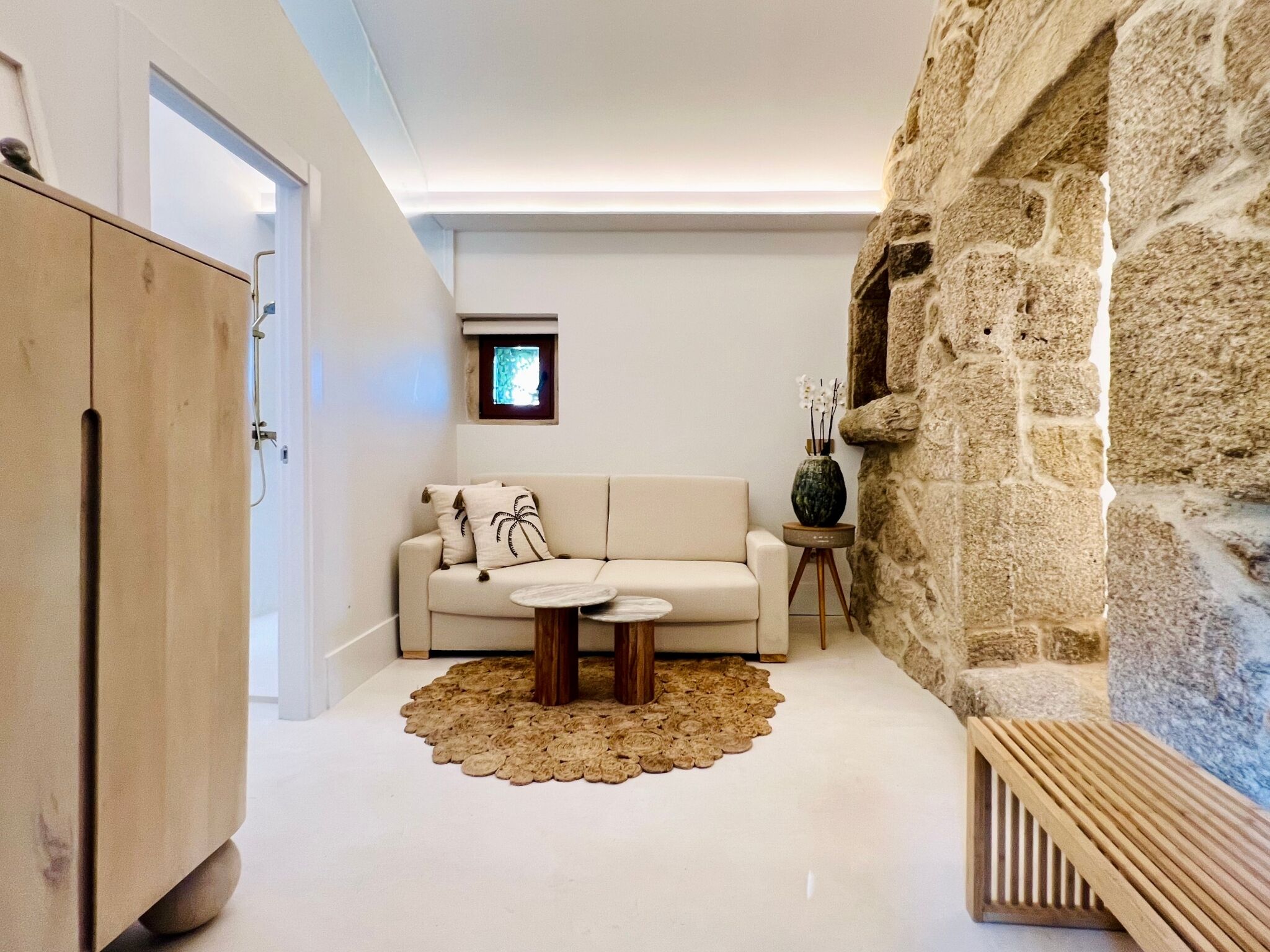 A modern living room with a sofa, two side tables, a decorative rug, and a stone wall.