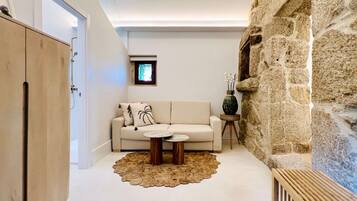 A modern living room with a sofa, two side tables, a decorative rug, and a stone wall.