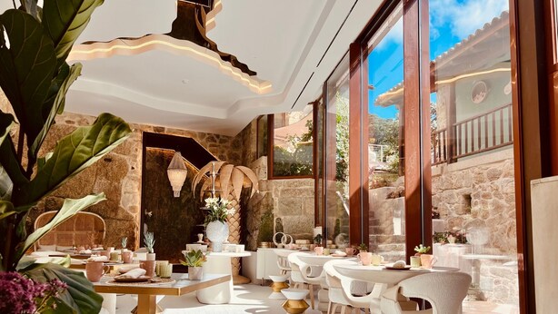 A modern outdoor dining area with stone walls, large windows, and contemporary furniture. - Aldea Calma (Sanxenxo)