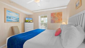 Ein Schlafzimmer mit Bett, Fernseher, Schminktisch und Bildern an den Wänden.