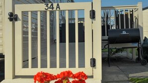 A beige gate with the number 34A, a barbecue grill, and red flowers in the foreground. - Cala Gran Holiday Park - Holiday Accommodation 10830 (Fleetwood)