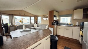 A compact RV kitchen with a central island, a sink, and a refrigerator. - Cala Gran Holiday Park - Holiday Accommodation 10830 (Fleetwood)