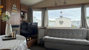 A caravan interior with a sofa, TV, and decorative items. - Cala Gran Holiday Park - Holiday Accommodation 10830 (Fleetwood)