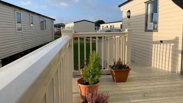 A mobile home with a balcony, potted plants, and a white railing. - Cala Gran Holiday Park - Holiday Accommodation 10830 (Fleetwood)