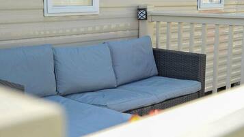 A wicker sofa with blue cushions on a deck.
