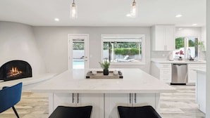 A modern kitchen with a central island, pendant lighting, a fireplace, and a view of the outdoors. - Spacious, Pet friendly Scottsdale Retreat with Pool (Tempe)