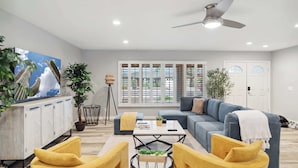 A modern living room with a sofa, yellow chairs, a coffee table, and a ceiling fan. - Spacious, Pet friendly Scottsdale Retreat with Pool (Tempe)