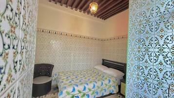 A bedroom with a bed, a chair, and a patterned wall.