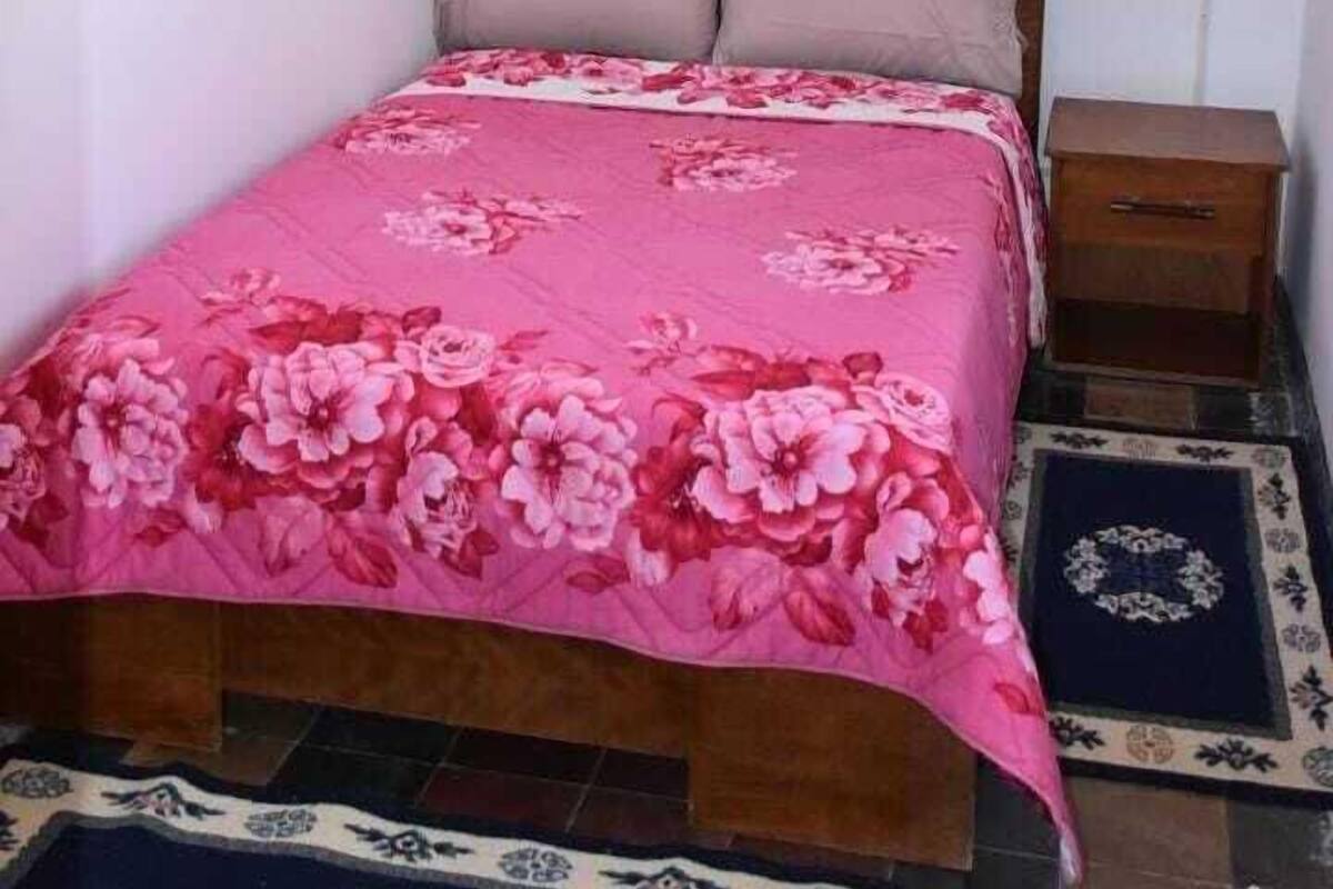 A bedroom with a bed, a nightstand, a decorative lantern, and a patterned rug.
