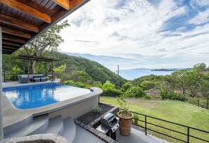 A swimming pool with a view of a mountainous landscape and a grill area.