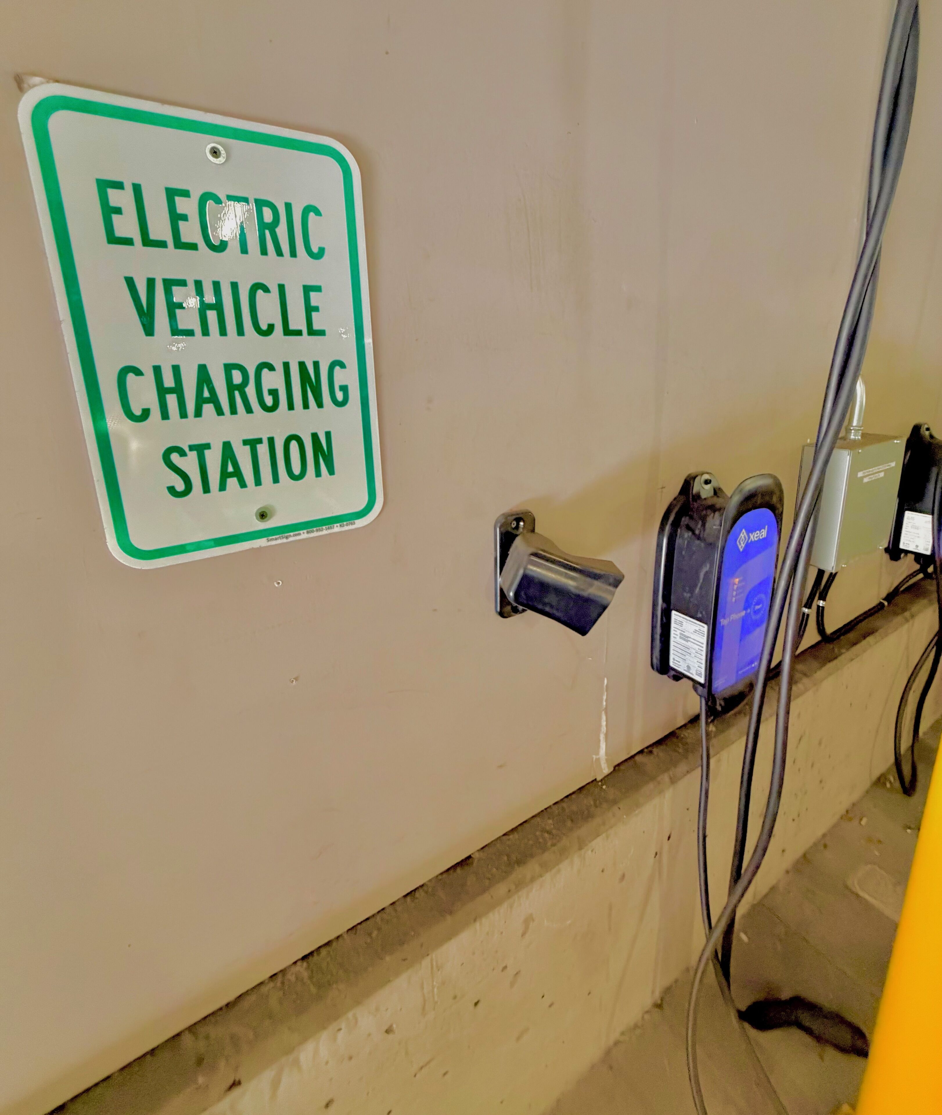 Eine Ladestation für Elektrofahrzeuge mit Schild, Ladeanschluss und Ladeeinspeisung.