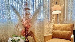 Ein gemütliches Zimmer mit rundem Tisch, einem Stuhl, einer Lampe und einer Zierpflanze.
