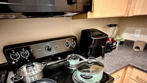 Eine Küche mit Herd, Töpfen, Mikrowelle und Kaffeemaschine.
