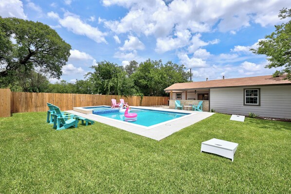Quintal com piscina, dois flamingos cor-de-rosa e cadeiras turquesa.