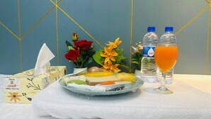Een ontbijfwagen met fruit, een glas sinaasappelsap en twee waterflessen op een tafel met een witte handdoek.