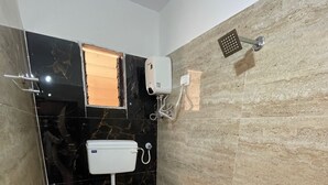 A bathroom with a toilet, sink, and shower. The walls are tiled with black and beige tiles.