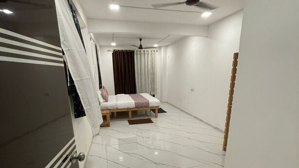 A bedroom with a bed, a ceiling fan, and a door with a striped pattern.