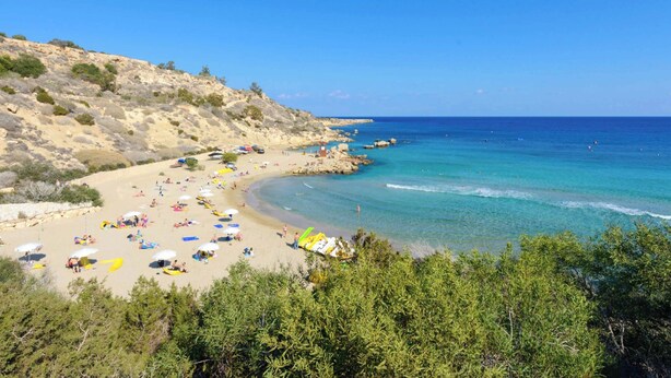 A beach with clear blue water, sandy shore, and green vegetation. - Villa Atlantis - Three Bedroom Villa, Sleeps 6 (Protaras)