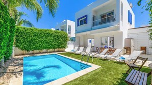 A modern two-story house with a swimming pool, a well-maintained lawn, and a patio area with lounge chairs. - Villa Atlantis - Three Bedroom Villa, Sleeps 6 (Protaras)