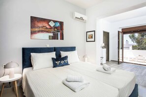 A modern hotel room with a large bed, a painting on the wall, and a view of the outdoors.