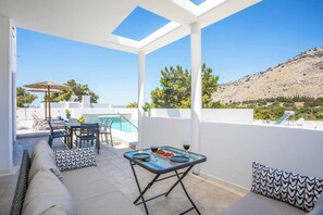 A terrace with a pool, outdoor seating, and a table with drinks.