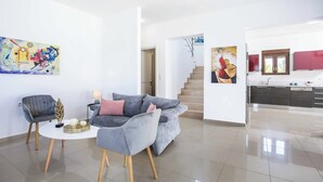 Un salon moderne avec un canapé gris, une petite table ronde et un tableau accroché au mur.