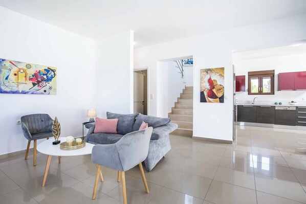 A modern living room with a grey sofa, a small round table, and a painting on the wall.