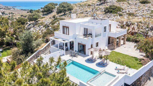 Une villa moderne dotée d’une piscine, d’un espace salon extérieur et offrant une vue sur la mer.