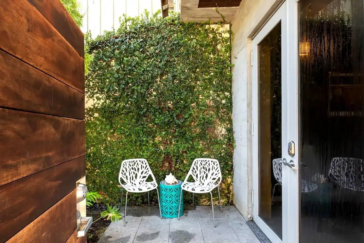 A patio area with two white chairs, a turquoise table, and a wooden fence.