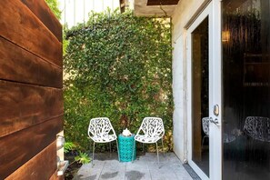 A patio area with two white chairs, a turquoise table, and a wooden fence. - Contra House Key West (Key West)