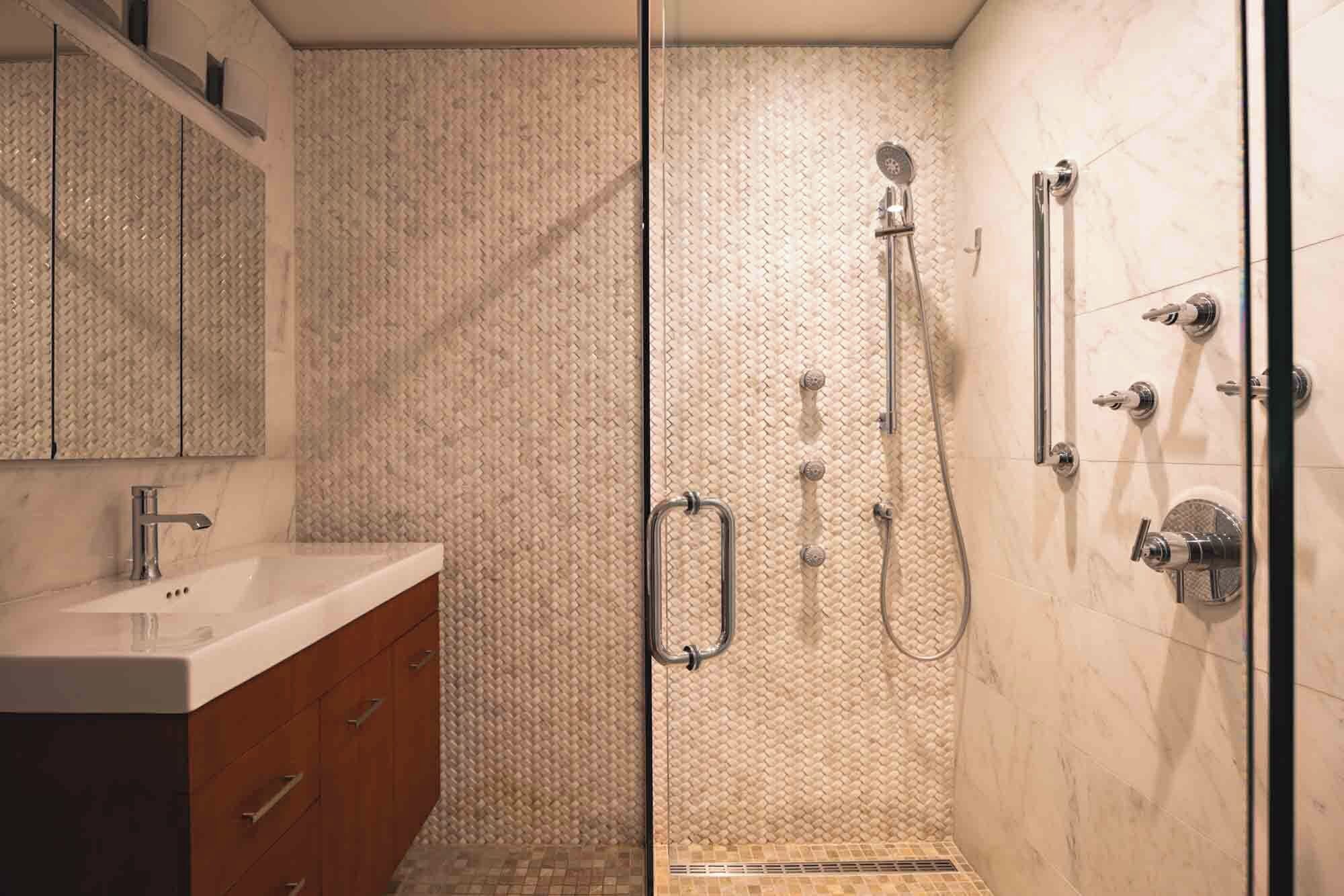 A modern bathroom with a glass shower enclosure, a vanity with a sink, and a mirror.