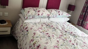 A bedroom with a bed, nightstands, a wooden shelf, and two wall-mounted lamps. - Freshwater Beach Holiday Park - Holiday Accommodation 17116 (Bridport)