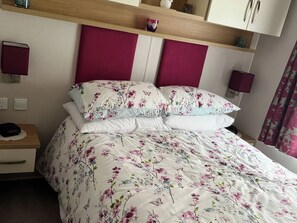 A bedroom with a bed, nightstands, a wooden shelf, and two wall-mounted lamps. - Freshwater Beach Holiday Park - Holiday Accommodation 17116 (Bridport)