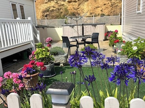 A backyard with a patio area, outdoor seating, and various potted plants. - Freshwater Beach Holiday Park - Holiday Accommodation 17116 (Bridport)