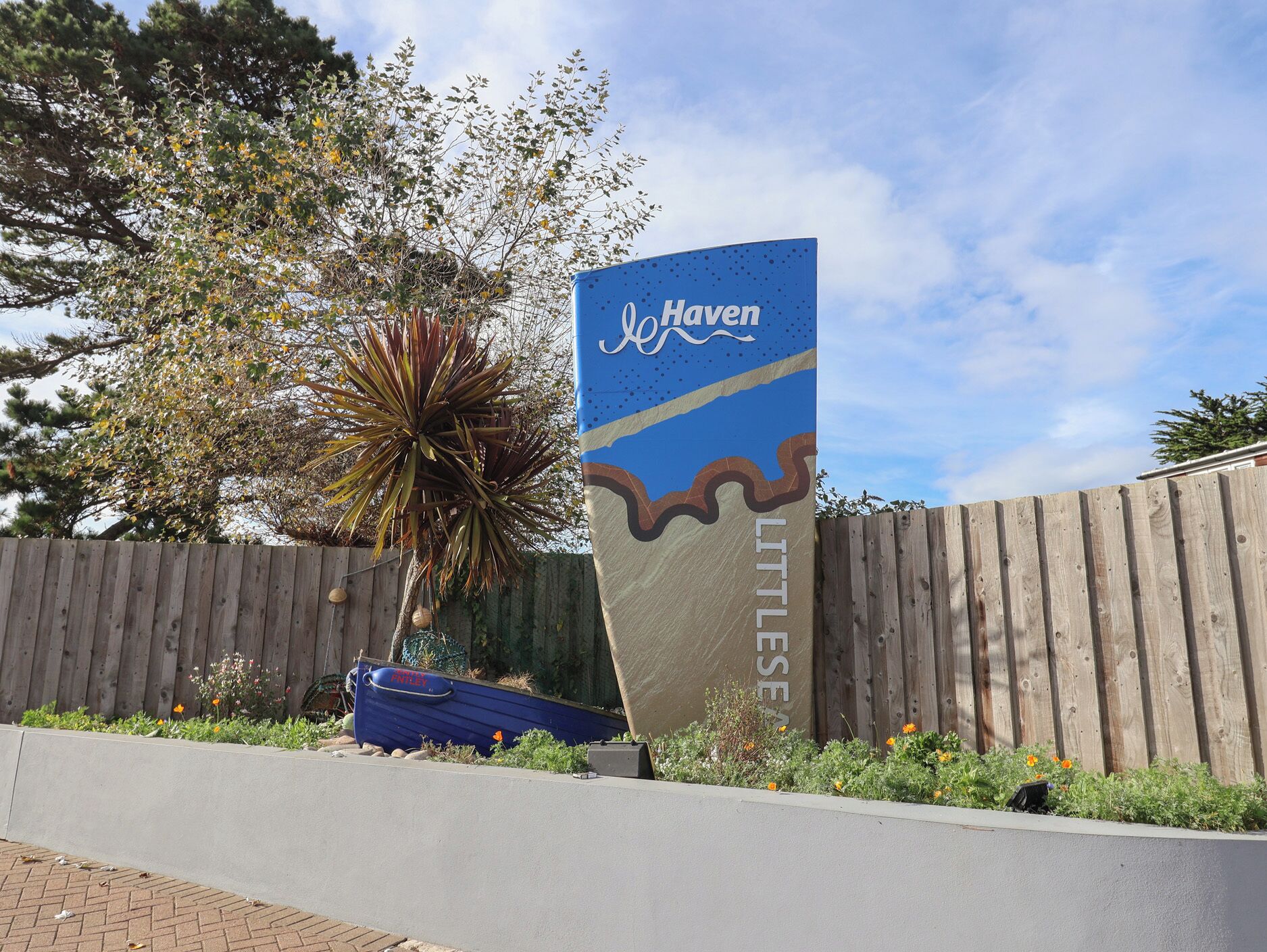 A sign for Haven Little Sea with a wooden fence and a plant in the foreground.