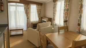 A cozy living room with a wooden table, two sofas, and a fireplace. - Freshwater Beach Holiday Park - Holiday Accommodation 12281 (Bridport)