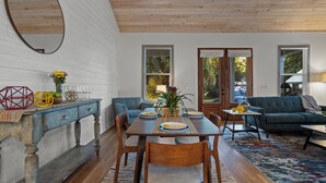 Un comedor con una mesa de madera dispuesta para cuatro personas, flanqueada por sofás azules y una mesa auxiliar.