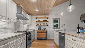 Una cocina moderna con armarios blancos, estantes de madera y una isla central.