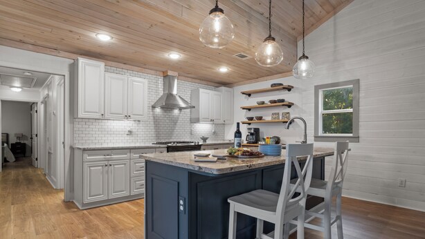 Una cocina moderna con gabinetes blancos, una isla central e iluminación colgante.
