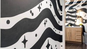 Una habitación con un diseño de pared ondulado en blanco y negro, un armario de madera y un suelo estampado.