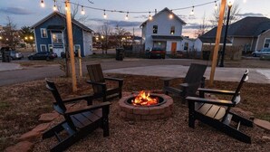 A fire pit with chairs arranged around it, set in a gravel area with a wooden border.