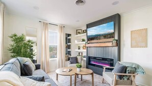 A modern living room with a fireplace, sofa, coffee table, and a large TV.