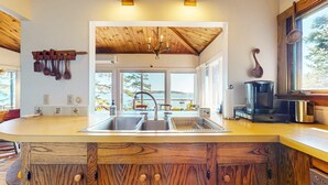 A kitchen with a wooden island, stainless steel sink, and a view of the outdoors.
