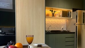 A modern kitchen with a microwave, refrigerator, and a tray with fruits and a cup. - Ibirapuera Park (São Paulo)
