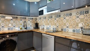 A modern kitchen with grey cabinets, a washing machine, a dishwasher, and a microwave. - Confort & Calme - Air-conditioned T2 with central courtyard (Carcassonne)