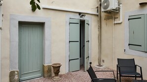 A building with multiple windows, a door, and outdoor seating. - Confort & Calme - Air-conditioned T2 with central courtyard (Carcassonne)