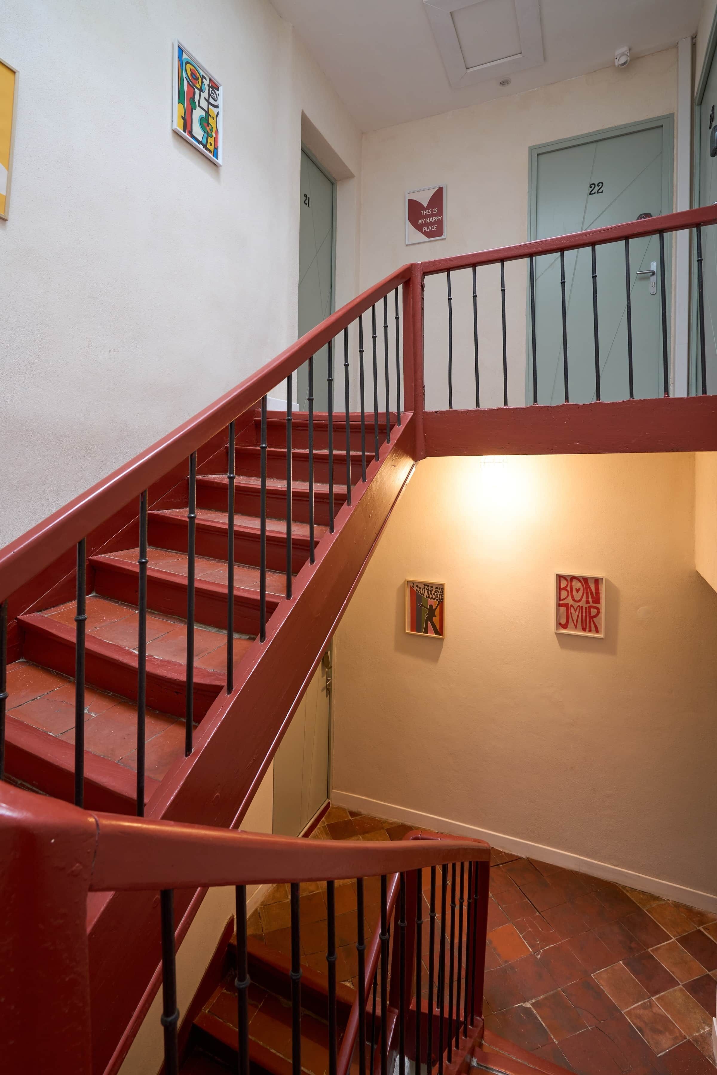 Eine Treppe mit roten Geländern und Handläufen, die zu einer Tür mit der Nummer 22 führt.