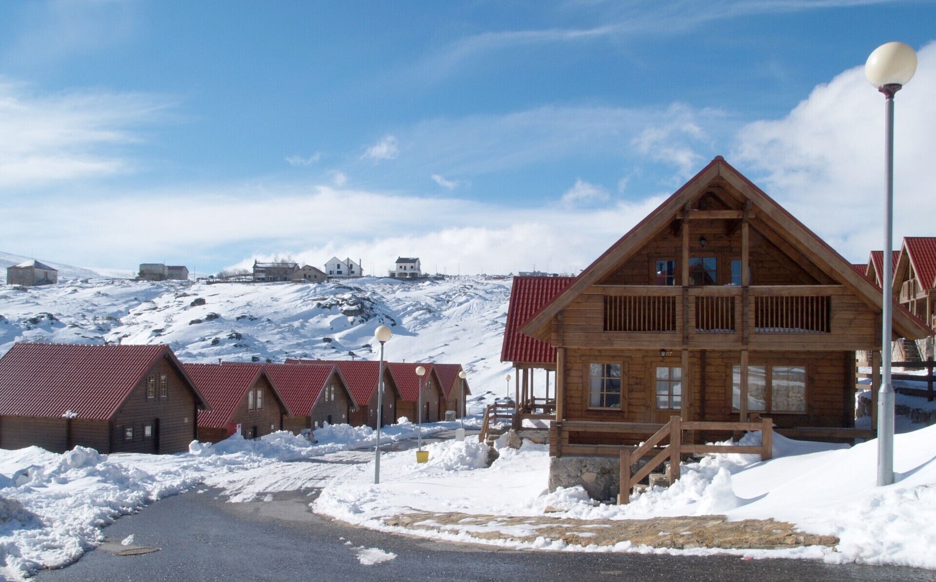 A wooden lodge with a steep roof, a stone foundation, and a snow-covered landscape.