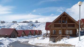 A wooden lodge with a steep roof, a stone foundation, and a snow-covered landscape.