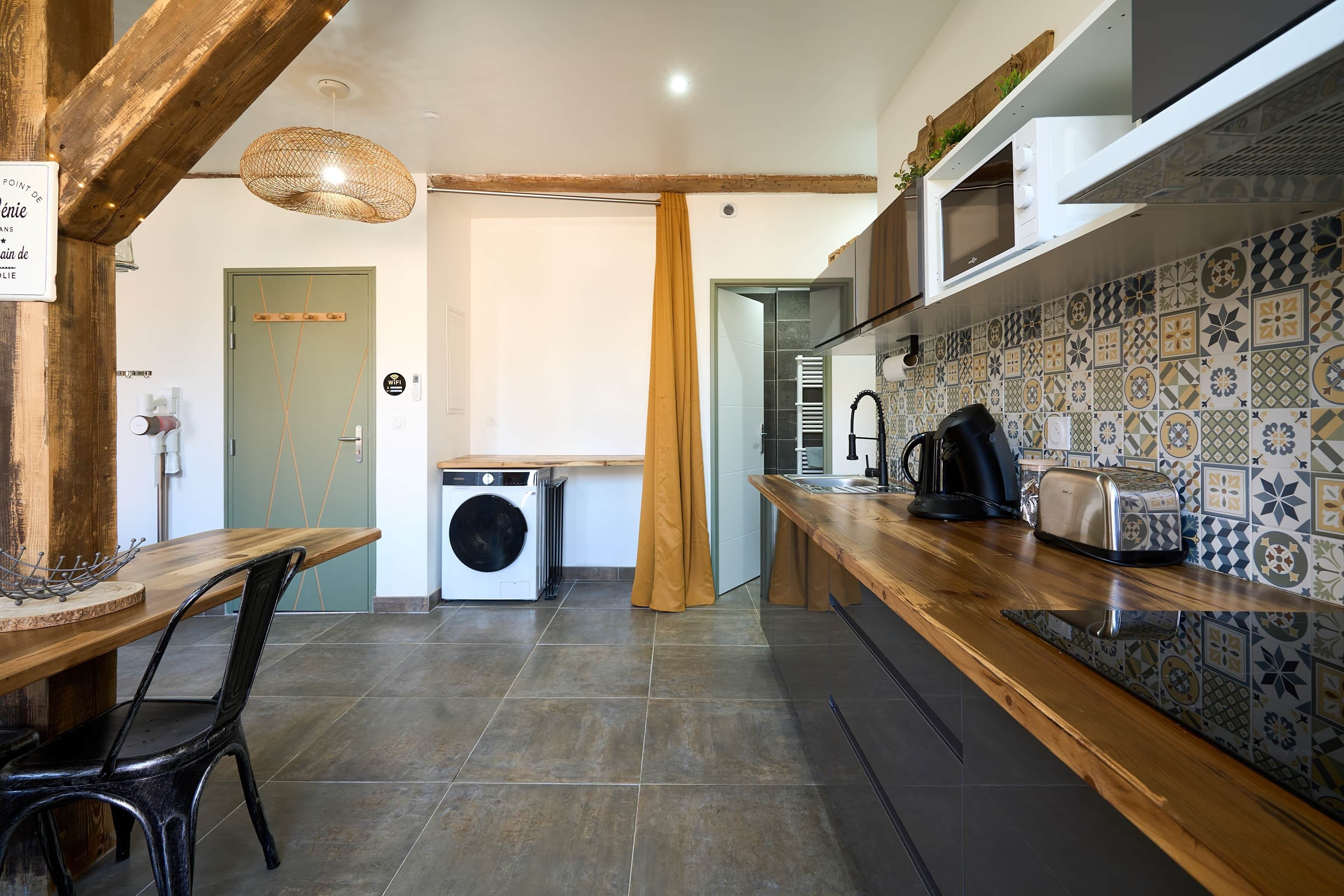 A modern kitchen with a built-in washing machine, wooden countertops, and patterned backsplash.